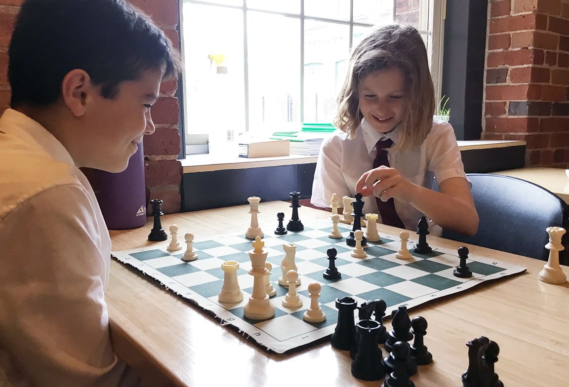 Picture of two junior schools students playing chess.