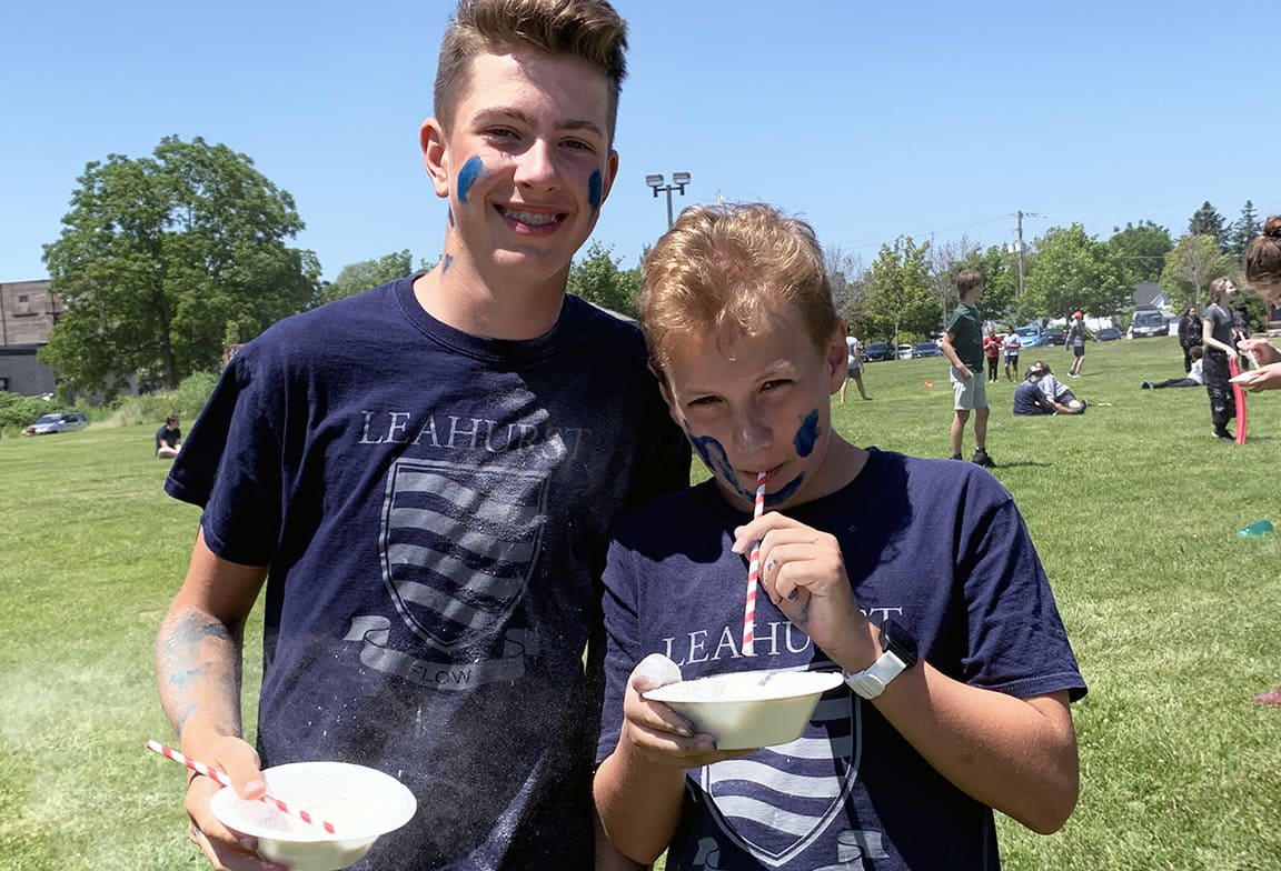 Picture of two students wearing Flow House t-shirt at an outdoor house activity