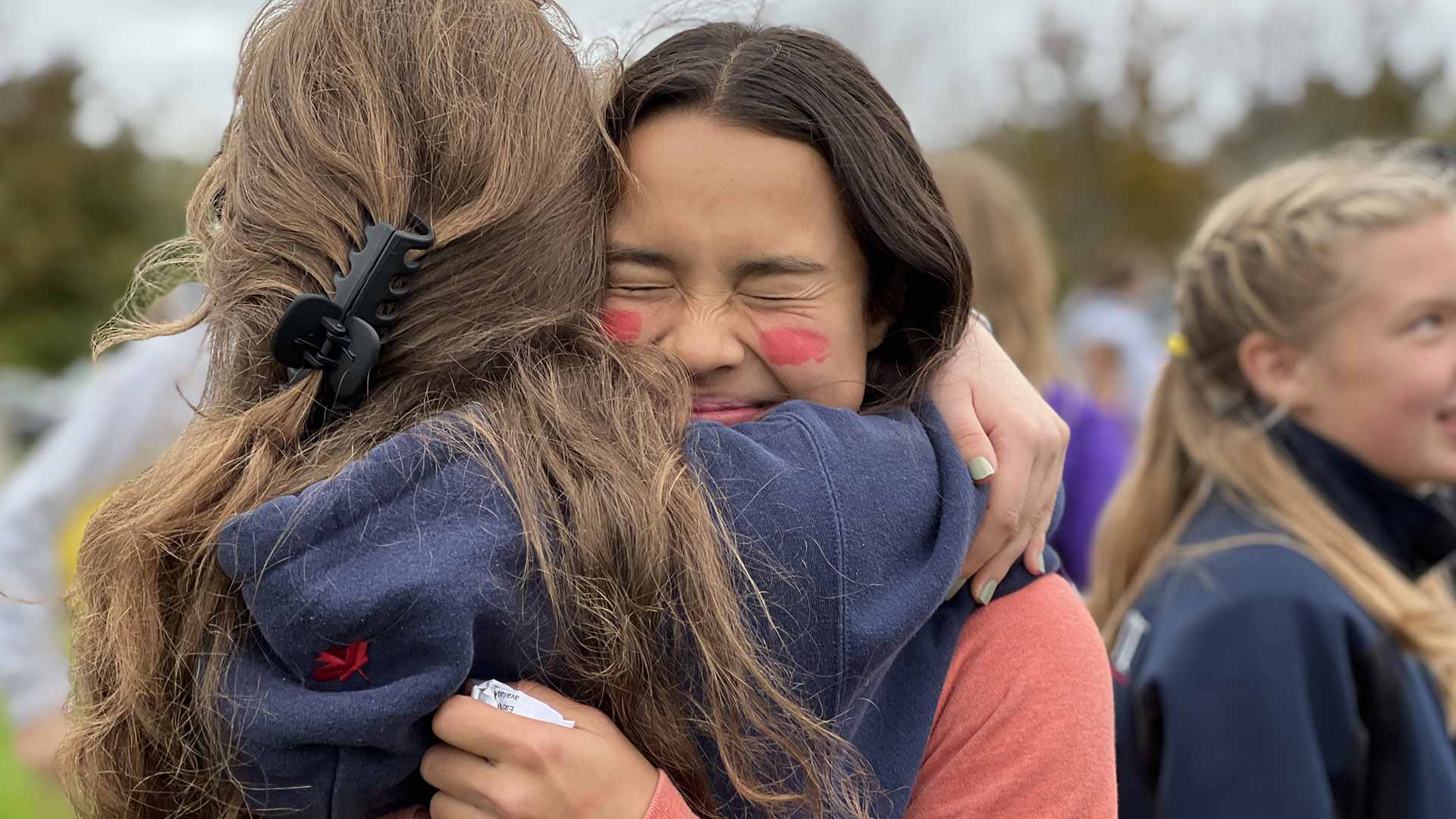 Picture of two students hugging while outdoors