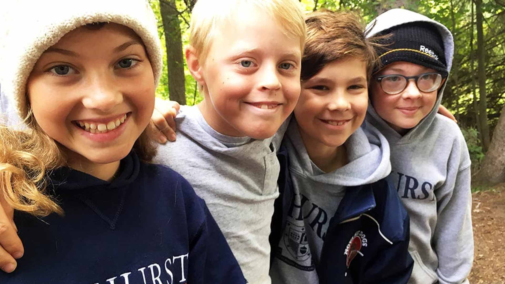Picture of four students outdoors in the woods smiling