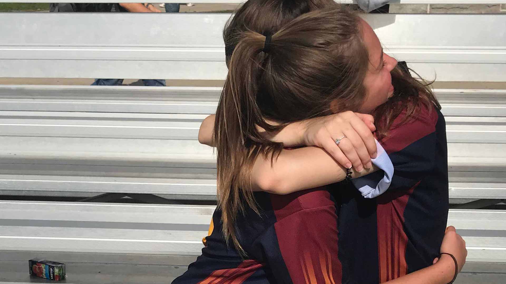 Picture of two students hugging in the bleachers at an athletic event