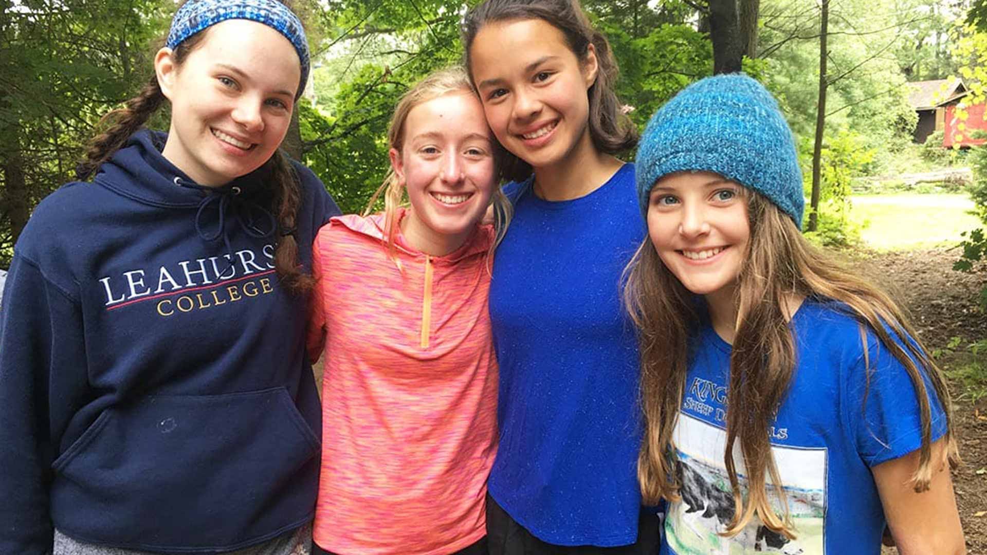 Picture of four students outdoors in the woods smiling