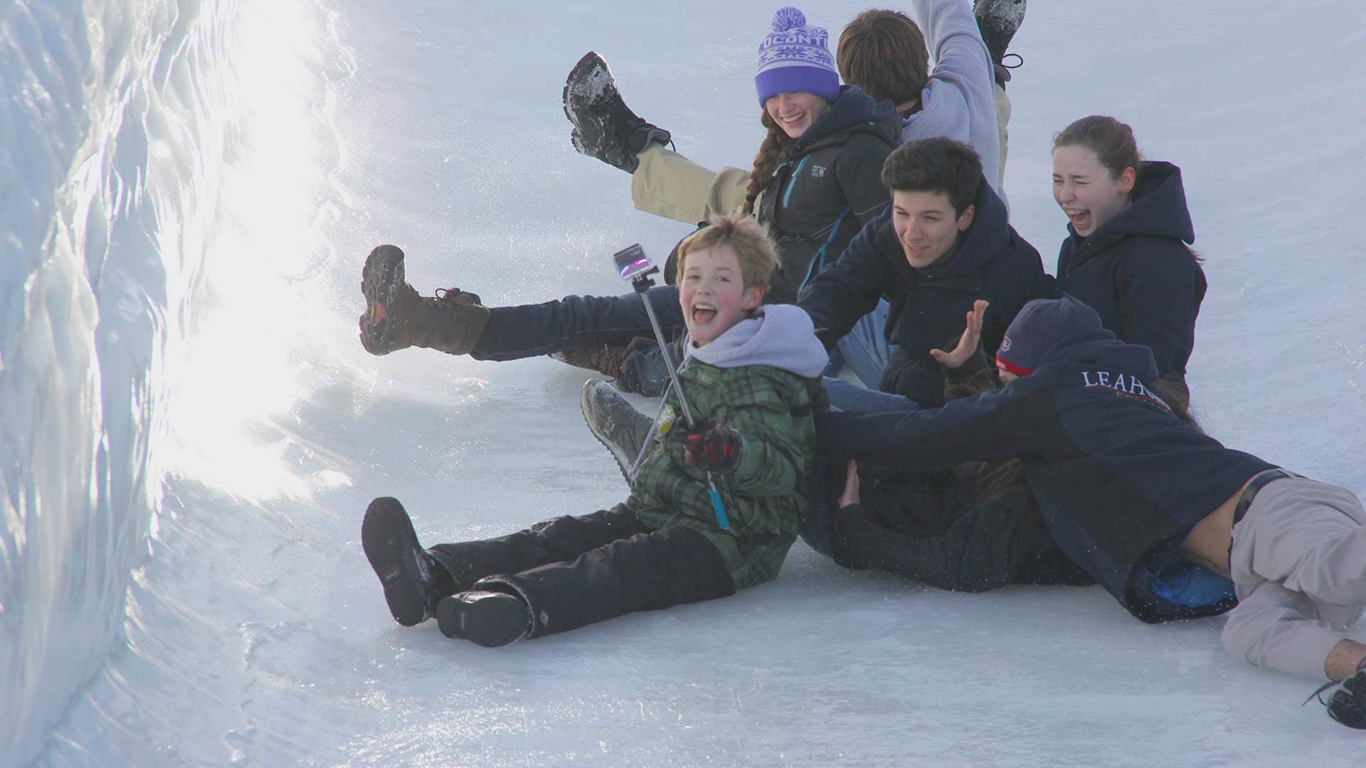 Picture of five students sliding down an icy hill outdoors in the winter