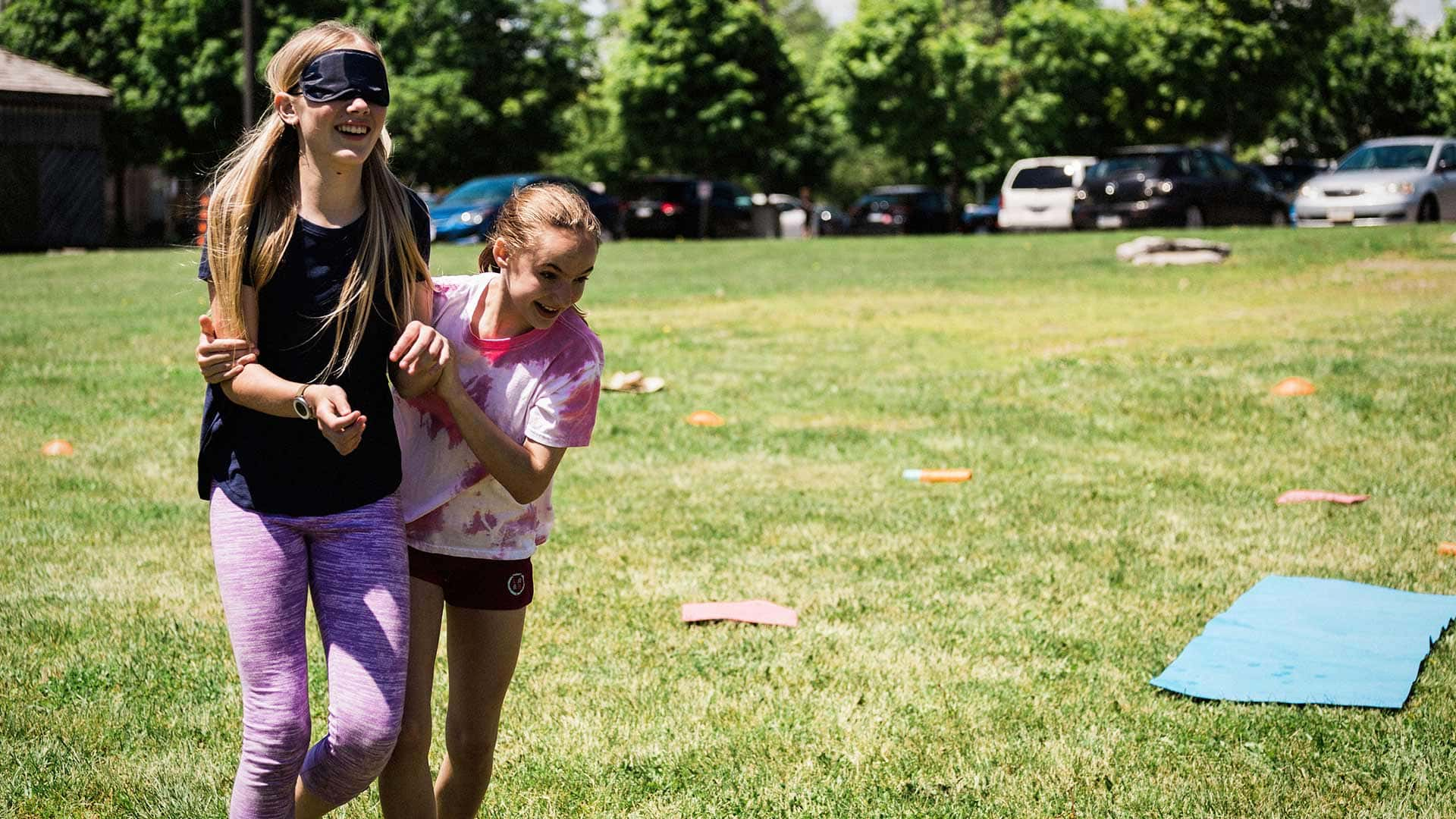 Picture of a student leading a blind-folded student through an activity outdoors