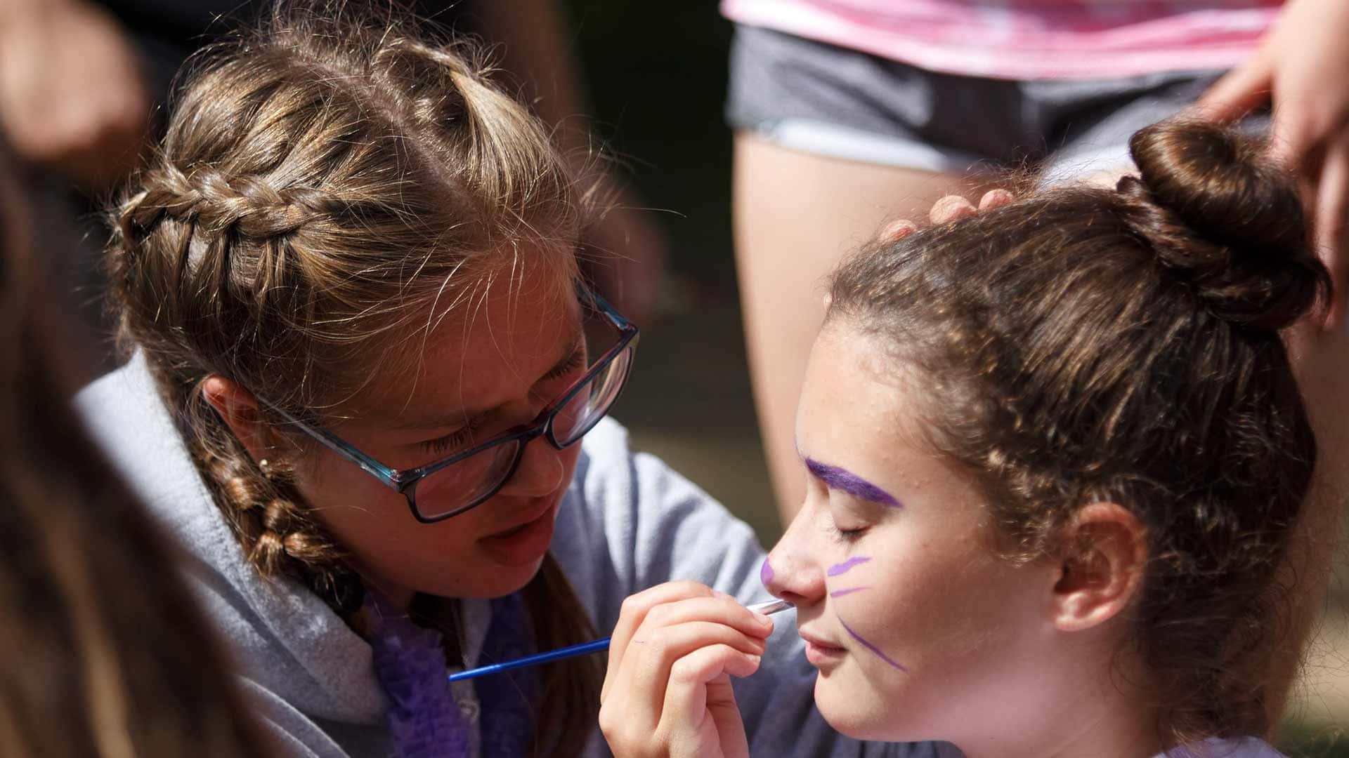 Picture of a students applying face paint to another student