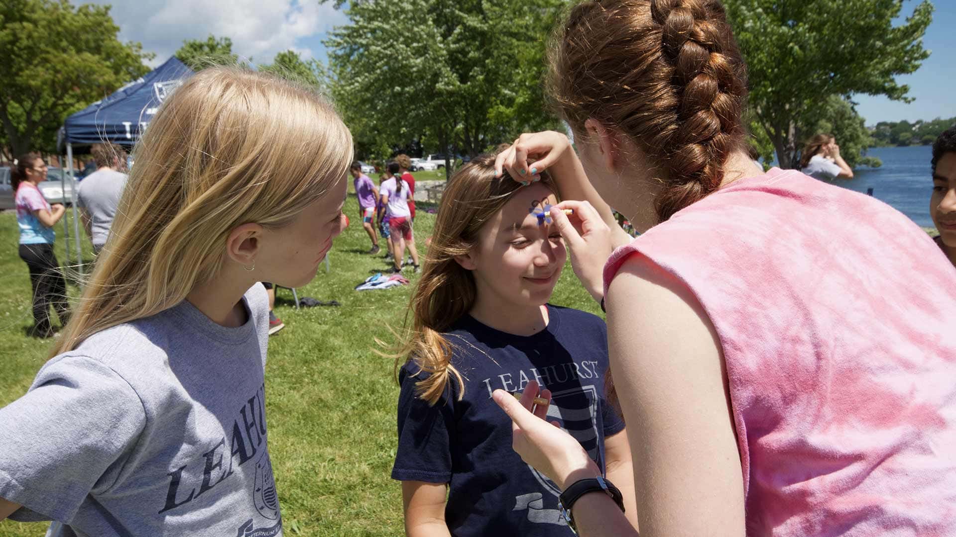 Picture of a students applying face paint to another student
