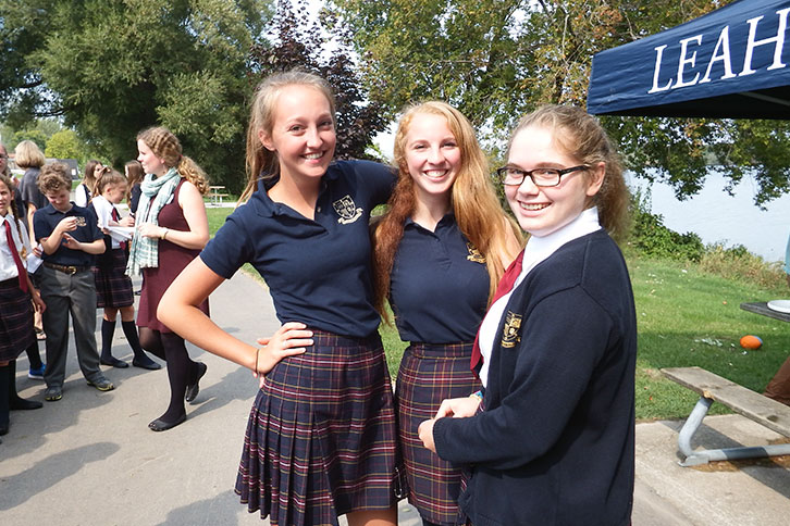 Picture of three students standing outside together at a school outdoor event