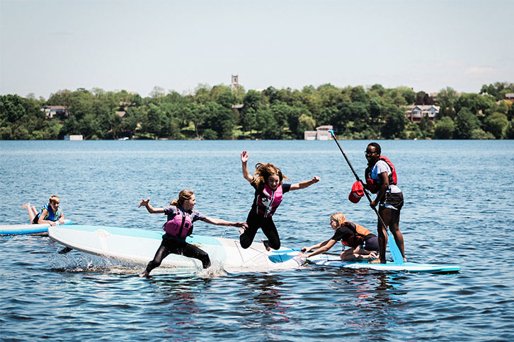Picture of five student paddles on a lake at an outdoor school activity