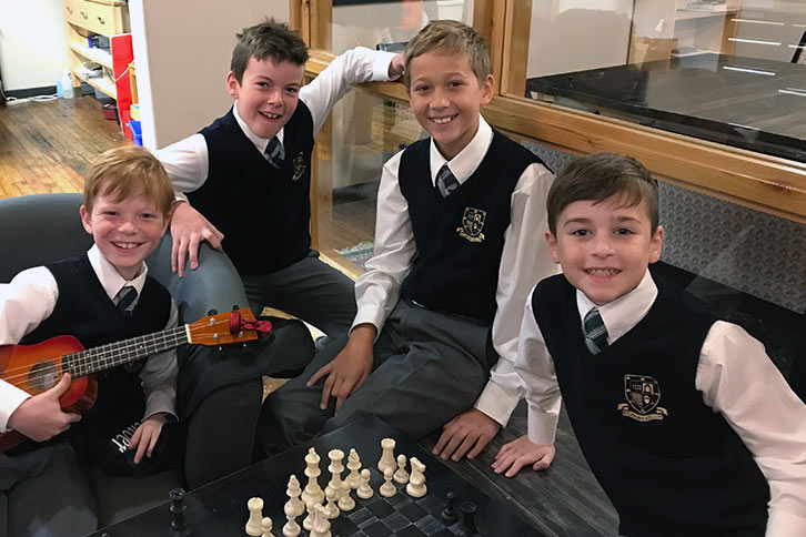 Picture of four junior school students sitting around a chess game