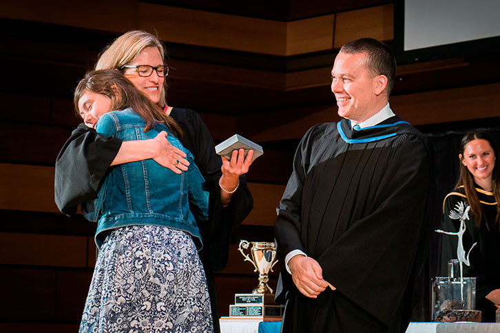 Picture of the head of school with a student at graduation.