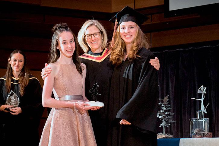 Picture of the head of school with students receiving their graduation diploma.