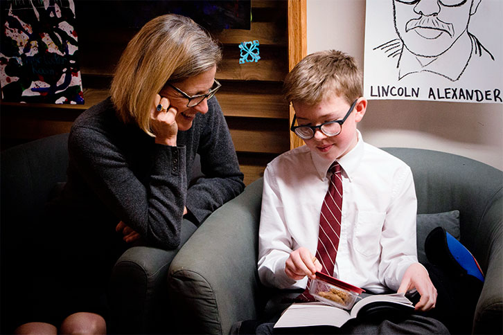 Picture of the head of school with a student that is pointing at something in a book.