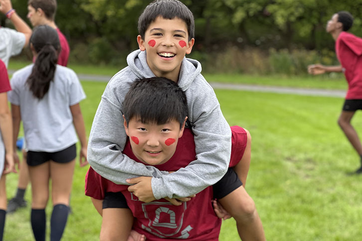 Picture of a student piggy-backing on another student outdoors