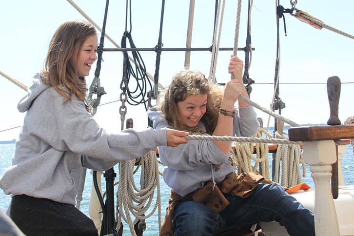 Picture of two students on a boat pulling on sails during a sailing course