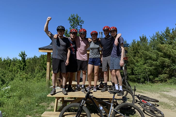Picture of a teacher with five students posing for a picture during a mountain bike outdoor activity