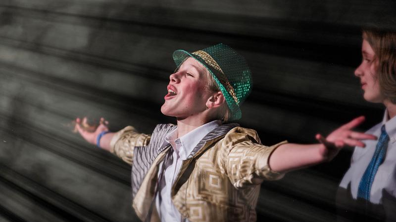 Picture of a student performaing and signing during a school play