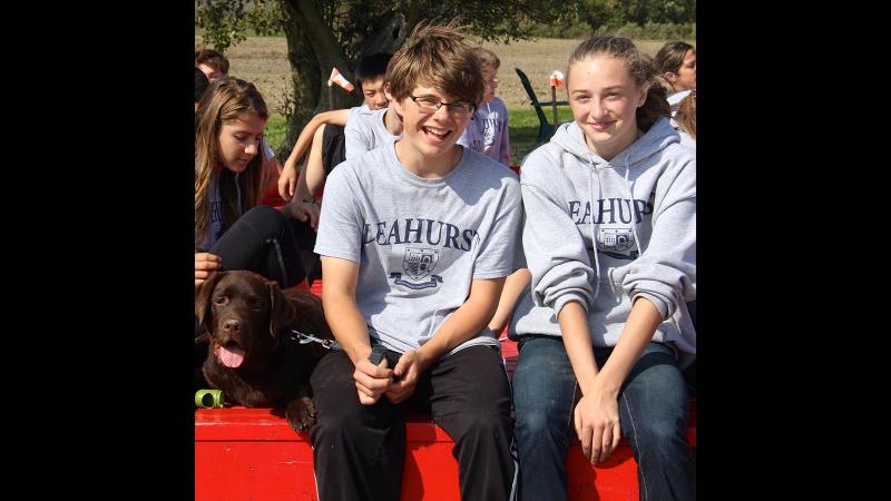 Picture of students sitting ourdoors with a dog