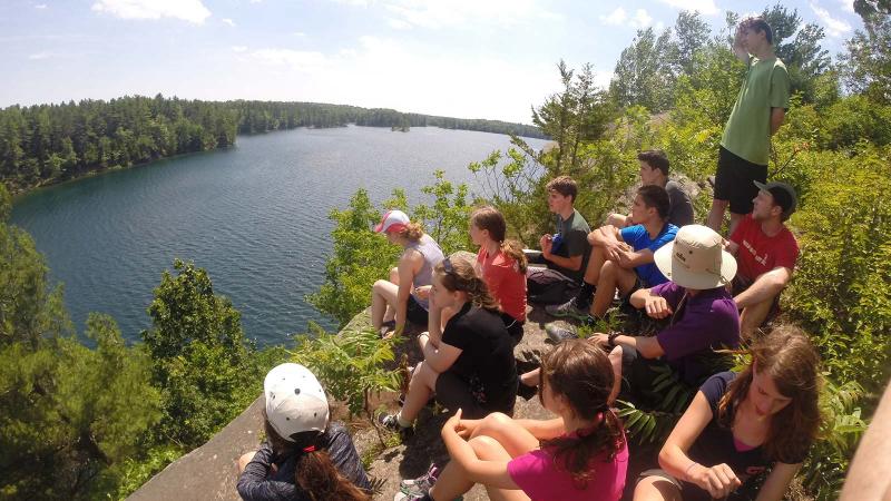 Picture of students sitting on a hill above a lake