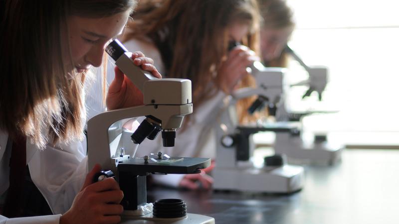Picture of students looking into microscopes in the science lab