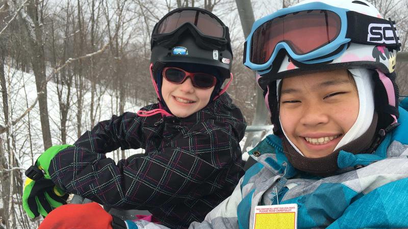 Picture of two student in sitting in a chair lift at a skiing activity