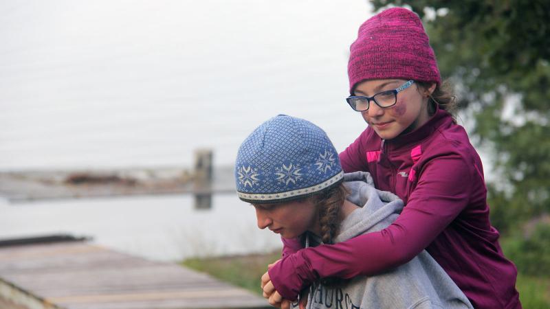 Picture of a student carying another student on their back outdoors