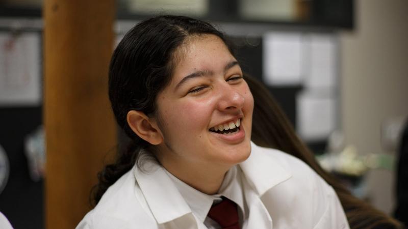 Picture of a student smiling in a lab coat in science class