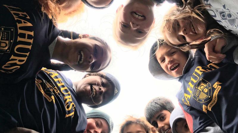 Picture of students in athletic gear in a circle looking down at the camera for a photo