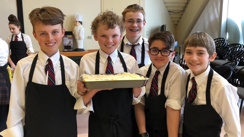 Picture of student posing for a photo and hold food they prepared during a field trip