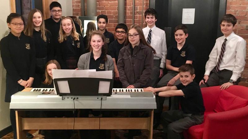 Picture of a group of student in music class around a piano