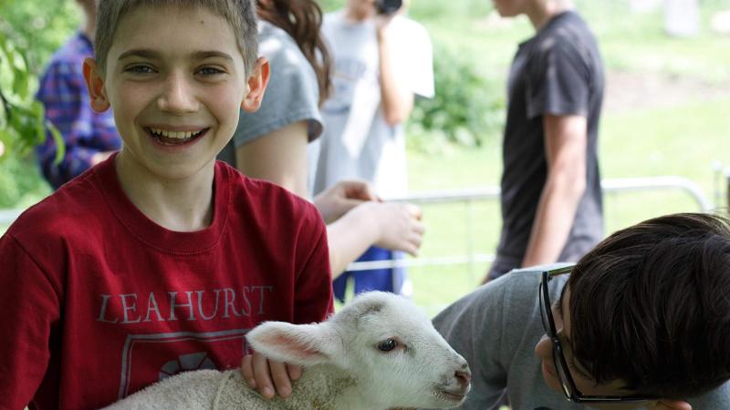 Picture of a student holding a baby sheep smiling