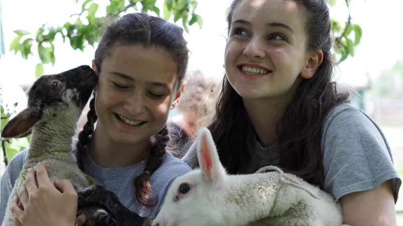 Picture of two students holding sheep outdoors