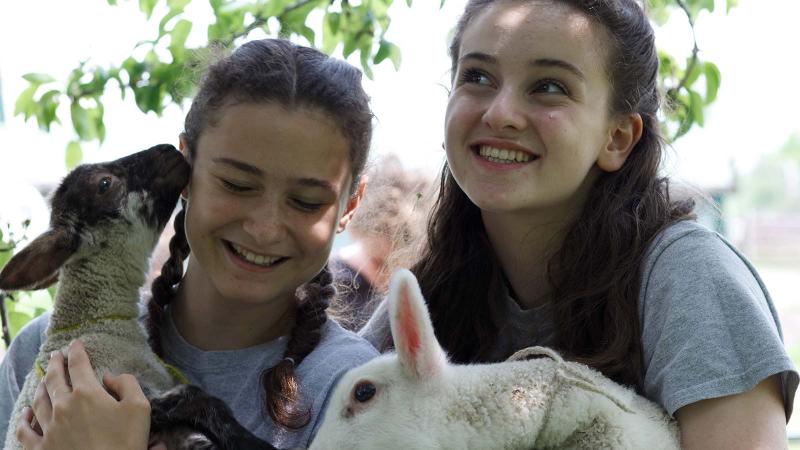 Picture of two students holding baby sheep