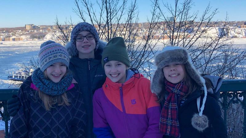 Picture of four students posing outdoors in the winter in front of a frozen lake