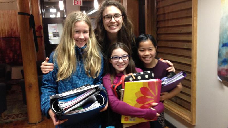 Picture of a teacher with threee students holding school books
