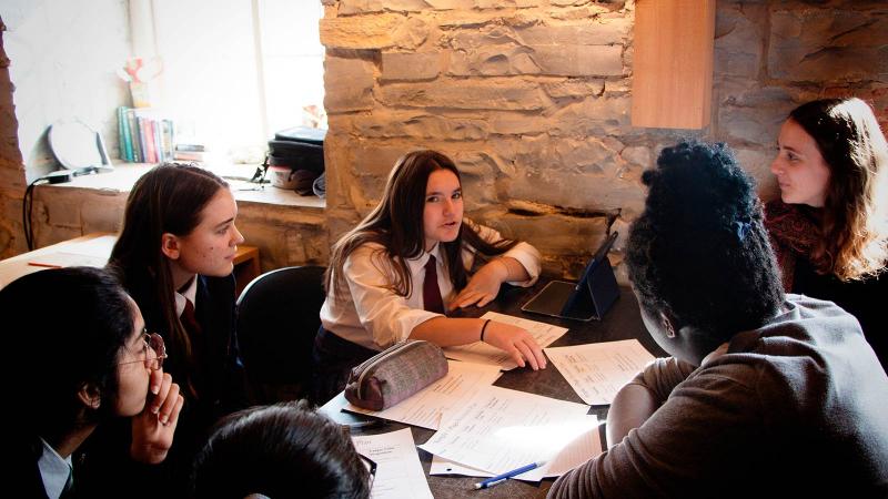 Picture of students sitting around a table in class working on school work