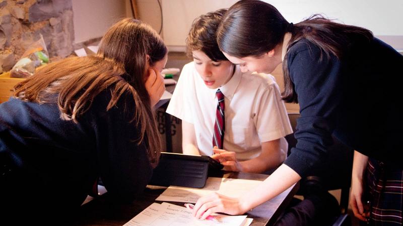 Picture of students sitting around a table in class working on school work