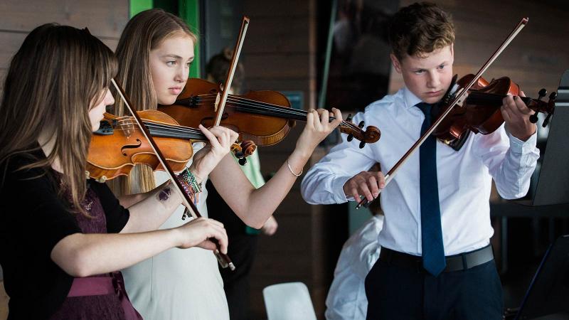 Picture of three student playing the violin