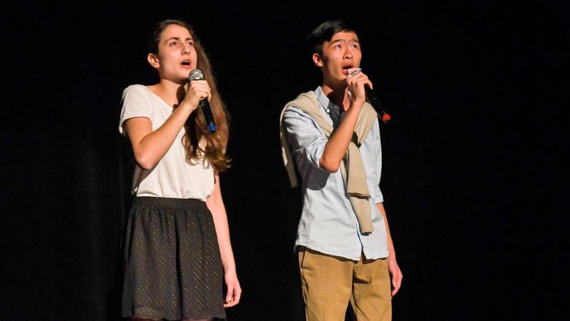 Picture of two students signing on stage