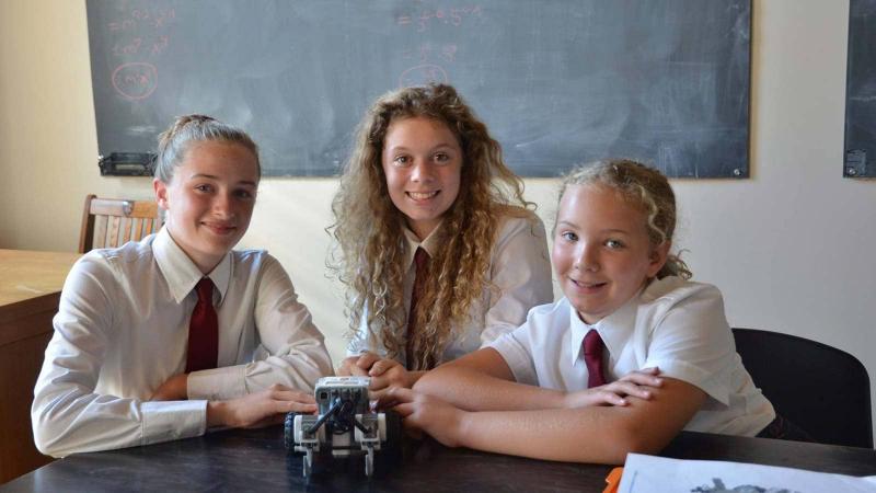 Picture of three students posing for a photo in a classroom