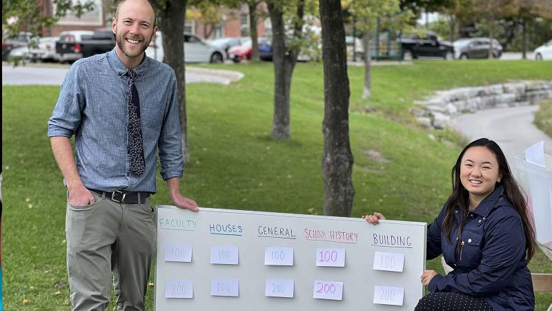 Picture of two teachers outdoor standing beside an board with posted notes