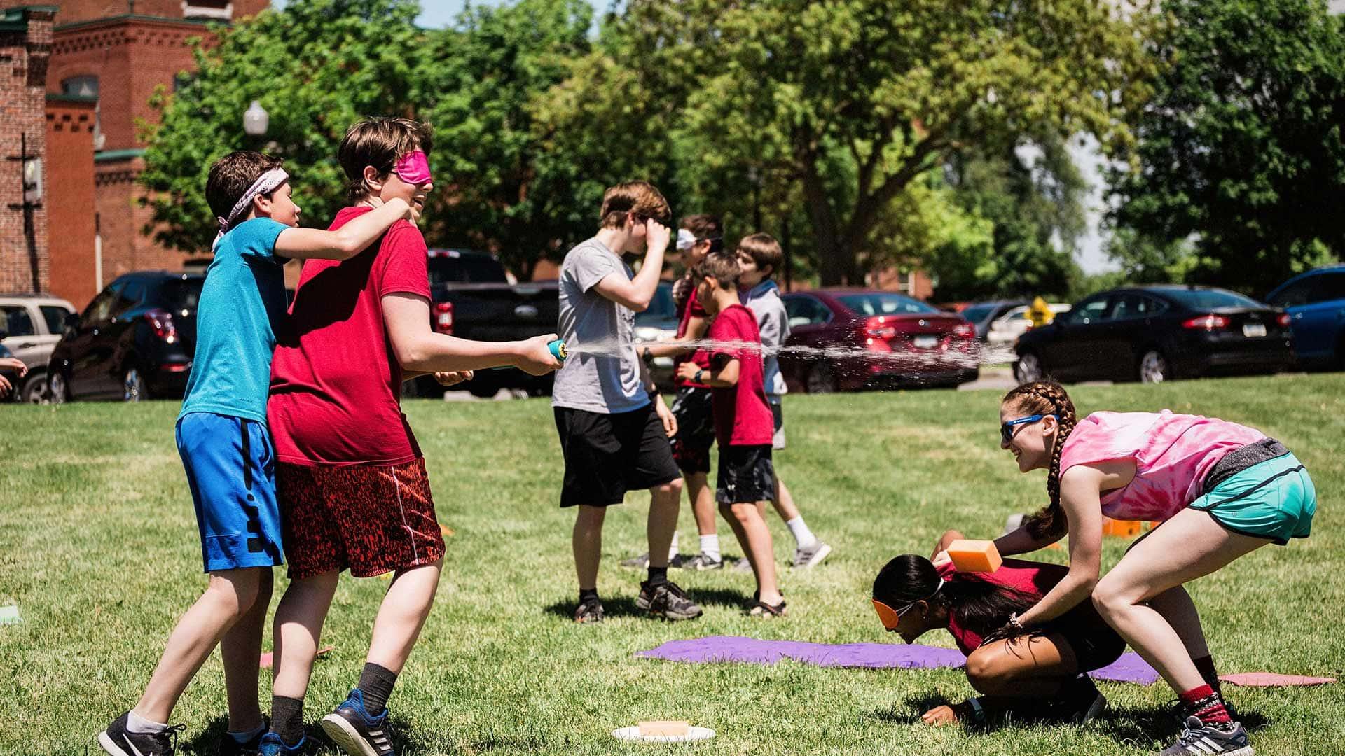 Picture of student in a water fight during a House event outdoors.